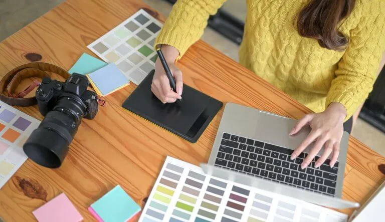 graphiste qui dessine sur une tablette avec un nuancier